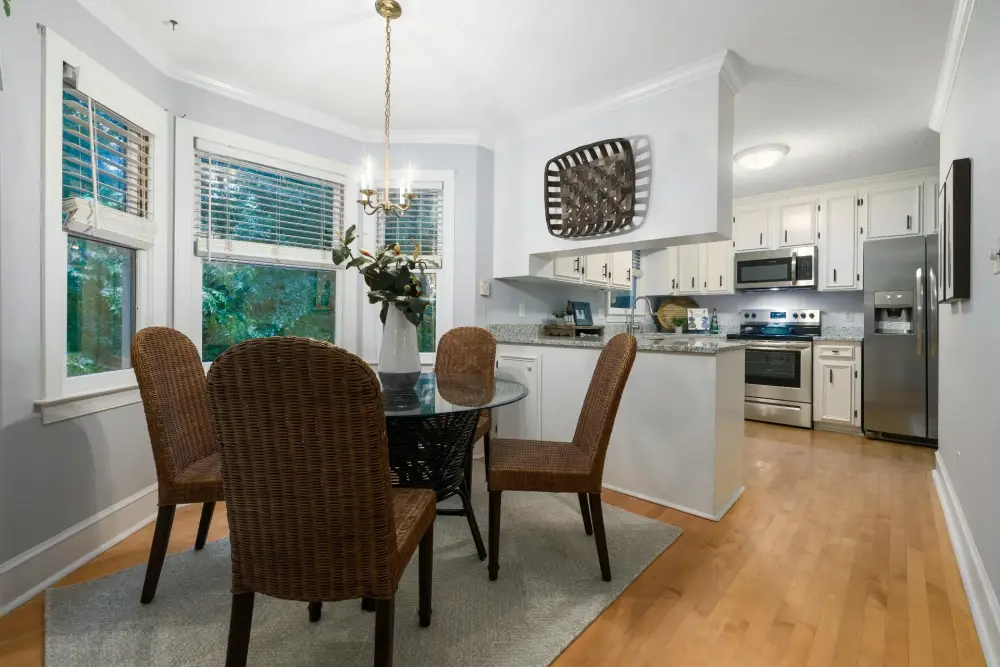Smiling professional cleaner in uniform organizing cleaning supplies in bright Portland home kitchen